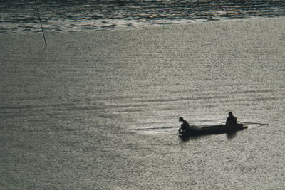 Silhouette men in boat on sea