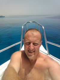 Portrait of shirtless man in boat on sea against sky