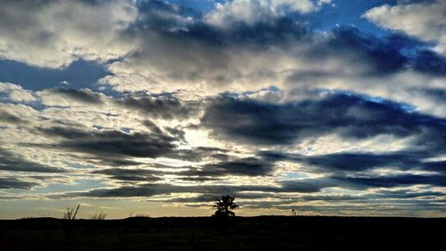 Silhouette landscape against cloudy sky