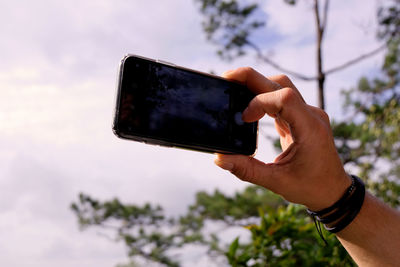 Man using mobile phone against sky