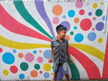 Full length of boy standing against multi colored wall