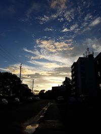 Vehicles on road against sky during sunset