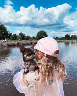 Woman with dog in water against sky