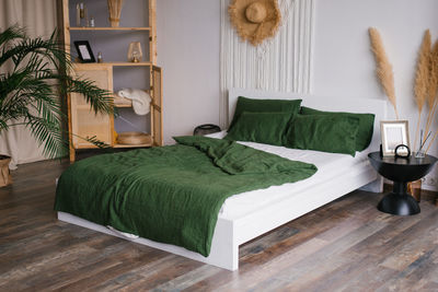 White green bedroom in boho style. a bed, a shelf with decor, a bedside table and a vase with pampas