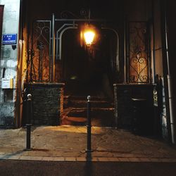 Illuminated street light by building at night