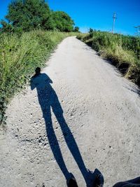 Shadow of man walking on road