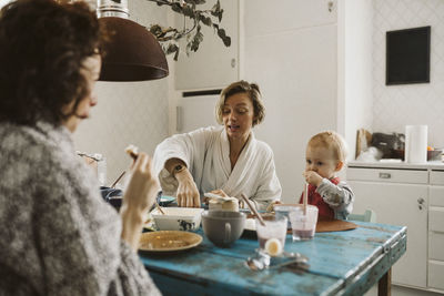 Woman talking with girlfriend while having breakfast at home