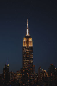 Illuminated empire state building in city at night