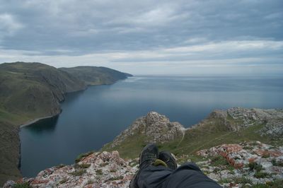 Low section of person on rock against sky