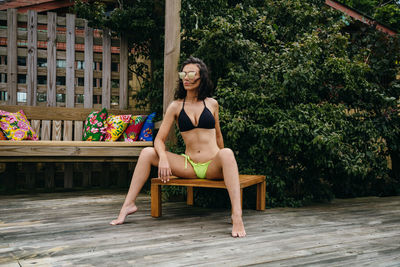 Portrait of woman sitting on chair against plants