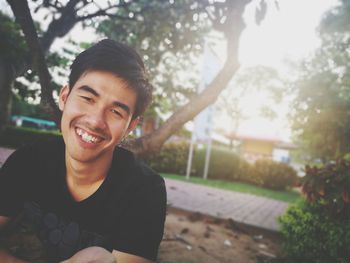 Portrait of smiling young man sitting at park