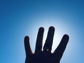 Low angle view of hand against clear blue sky