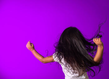 Rear view of woman against purple wall