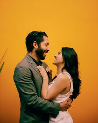 Side view of couple standing against orange wall