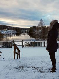 Woman standing on snowy field against sky during sunset