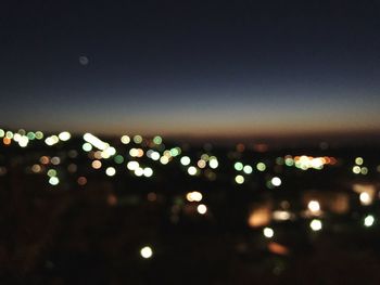 Defocused image of illuminated city against sky at night