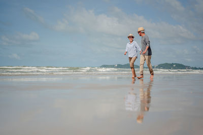 Full length of men at beach against sky