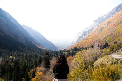 Rear view of woman standing on mountain against sky