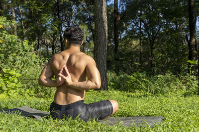 Latin american man doing yoga posture, yoga posture, bee backwards prsthatah brahmara, forest