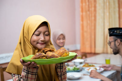 Girl smelling food in plate at home