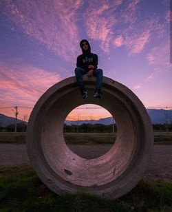 Man standing on field against sky during sunset