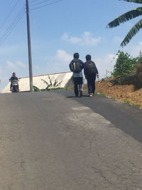 Rear view of people walking on road