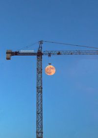Low angle view of crane against clear blue sky