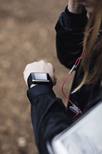 Cropped image of female athlete checking fitness tracker in forest