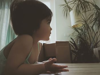 Side view portrait of boy sitting on table at home