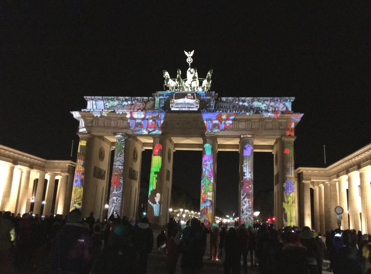 architecture, built structure, building exterior, large group of people, night, illuminated, person, men, history, travel destinations, low angle view, lifestyles, famous place, clear sky, tourism, leisure activity, facade, tourist, crowd