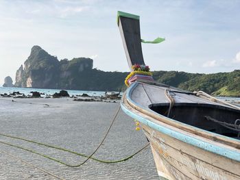 Longtail boat at beach against sky