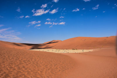 Sand dunes in desert against blue sky