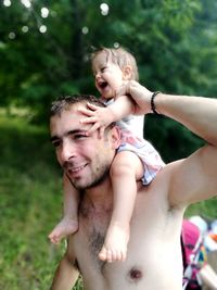 Close-up of father carrying daughter on shoulder at park