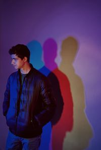 Full length of young man standing against purple wall