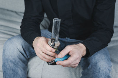 Midsection of man holding lighter and marijuana pot