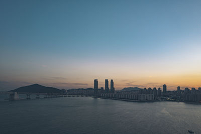 View of buildings by sea against sky during sunset