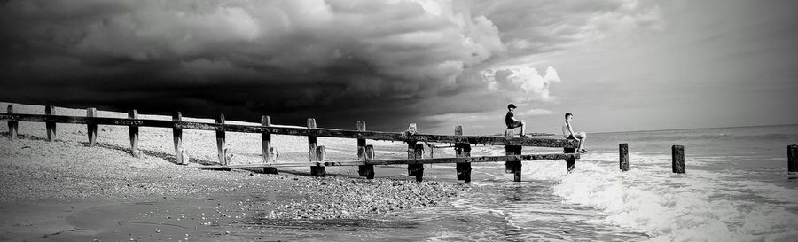 Panoramic shot of man on pier over sea against sky