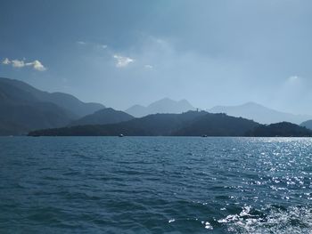 Scenic view of sea by mountains against sky