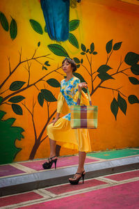 Portrait of female model standing against patterned wall