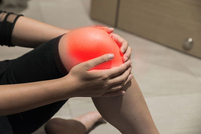 Digital composite image of woman holding knee in pain on floor
