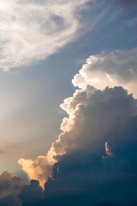 Low angle view of sunlight streaming through clouds