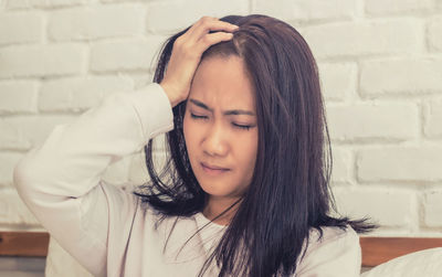 Portrait of young woman against wall