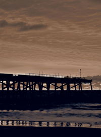 Silhouette pier over sea against sky during sunset