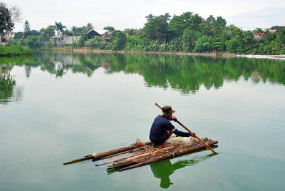 Man sailing on wooden raft in lake