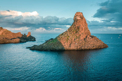 Rock formation in sea against sky