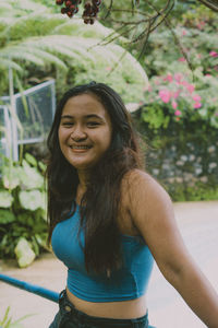 Portrait of young woman standing against trees