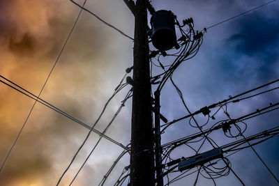 Low angle view of silhouette electricity pylon against sky