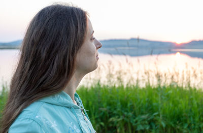 Side view of young woman looking away against sea