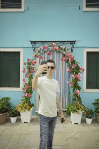 Full length of woman standing by potted plant against building