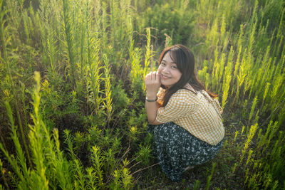 Smiling young woman holding corn on field